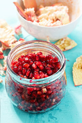 Pomegranate seeds in jar with membrane and skin in bowl left in the background