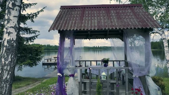 The view on decorated arbor with chiffon and flowers for wedding ceremony.