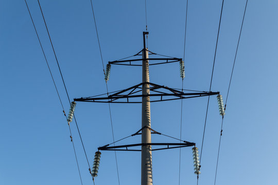 Support with electric wires against the blue sky.