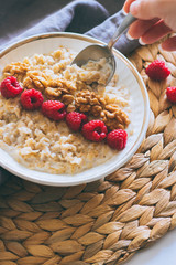 Morning breakfast, oatmeal in milk with raspberries and walnuts