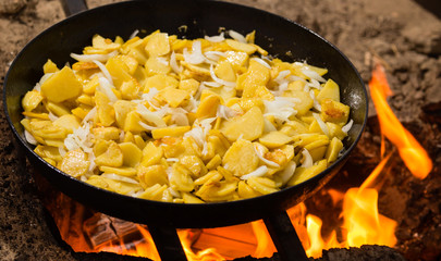 Potatoes fried in a frying pan in the open air