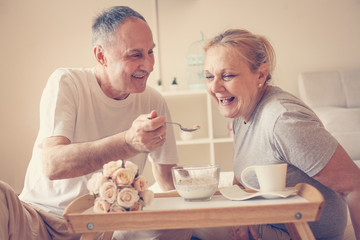 Senior couple having healthy breakfast together in bed.