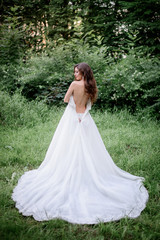 Fototapeta premium Look from behhind at bride taking off her dress standing in the garden