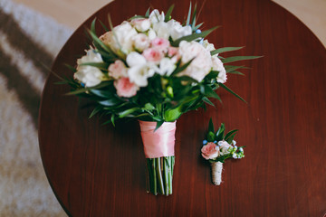 Beautiful bouquet of flowers of the bride and boutonniere lie on the table