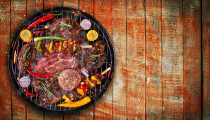 Top view of fresh meat and vegetable on grill placed on wooden planks