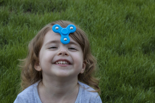 portrait little beautiful girl is playing blue spinner.