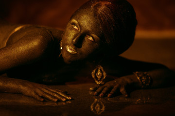 Dreamy woman with bronze skin lies on the glass floor