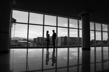 Fototapeta na wymiar silhouette of Businessman and Businesswoman shaking hands in office with big panoramic windows, Business concept.