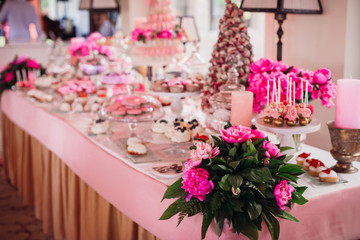 Dishes with tasty cookies with pink icing and berries stand on the candy bar