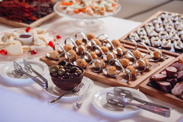 Spoons with snacks and little bowls with olives served on white table