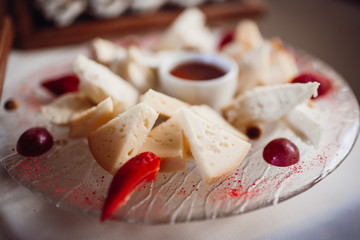 Pieces of cheese and berries served on the plate with red sauce