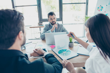 Obraz premium Brainstorm concept. Group of three business partners are discussing the project at nice modern office. They are all serious and concentrated. Boss is asking subordinates about report