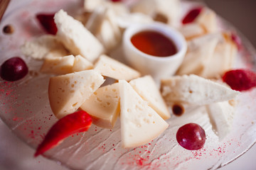 Pieces of cheese and berries served on the plate with red sauce