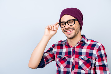 Dreamy student hipster in a casual checkered shirt, black glasses, hat, smiling and looking at the...