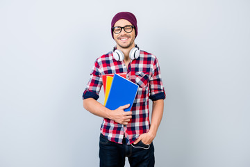 Smiling young nerdy stylish student hipster is standing with books on pure background in black...