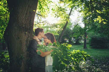  Handsome young man standing in park  and kissing his girlfriend on forehead