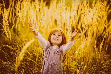 Little girl with red hair stands on the autumn field