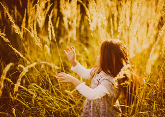 Little girl with red hair stands on the autumn field