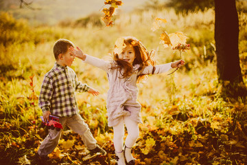 Children play with fallen leaves in the evening