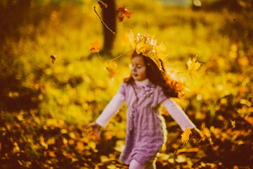 Girl plays with fallen leaves in the evening
