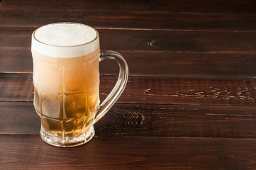 glass of cold frothy lager beer on old wooden table