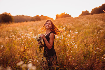 Obraz premium Happy woman with flowers stands on the evening field