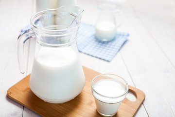 milk and glasses of milk on a wooden rustic table.