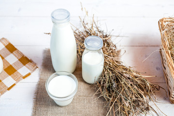 milk and glasses of milk on a wooden rustic table.