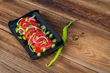 Salad of tomato and pepper on a wooden background