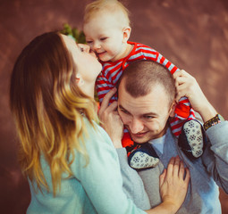 Mom and dad have fun with their son standing in a room with Christmas tree