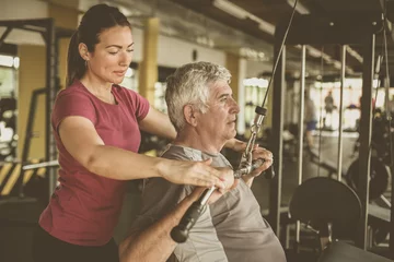 Poster Personal trainer working exercise with senior man in the gym. People workout in gym. © liderina
