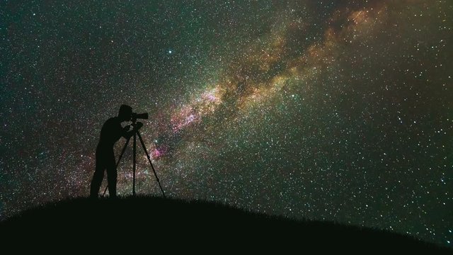 The photographer with a camera stand against the milky way. time lapse