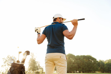Back view of a male golf player at the course with a club sack