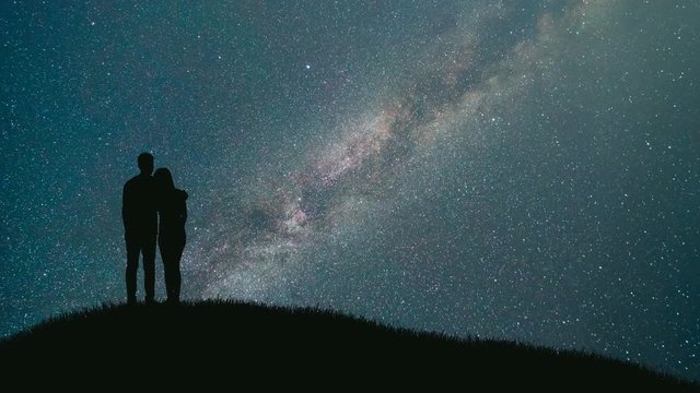 The couple stand against the sky with a meteor shower. time lapse, night time