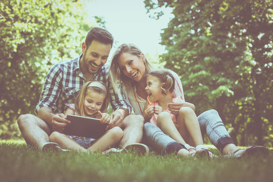 Happy family with two children in meadow using digital tablet together. Family in meadow.