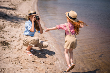 mother photographing daughter on beach