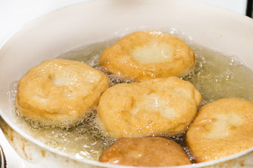 Frying donuts in hot oil. Homemade domestic donuts preparing in hot oil