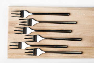 Flat lay above set of metal forks on the wooden board