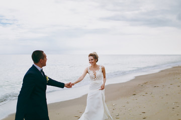 Fototapeta na wymiar Groom and bride on a walk outdoors at the sea