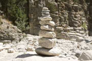 Harmony and balance, poise stones against the rock in the mountains, rock zen sculpture, three grey pebbles, sunny day
