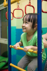 Obraz premium Asian Chinese little girl hanging on rings