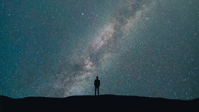 The man stand on a background of a milky way with asteroids skyfall. time lapse