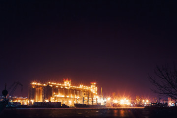 Fototapeta na wymiar Panorama image of the illuminated cargo port at night, cargo ships and cranes