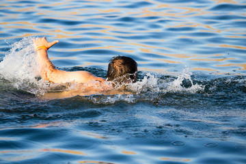 Obraz na płótnie Canvas The man is swimming in the lake