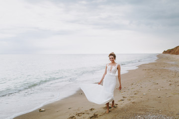 Beautiful blonde bride on a walk by the sea