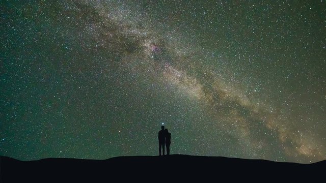 The couple stand against the milky way with asteroids skyfall. time lapse