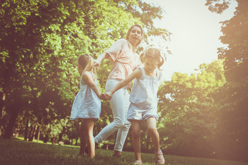Fototapeta premium Mother playing on meadow with her two little daughter.