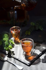cup of tea in sunny morning. green fresh leaves on the table