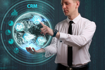 Obraz premium Business, Technology, Internet and network concept. Young businessman working on a virtual screen of the future and sees the inscription: CRM