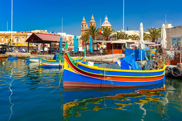 Traditional eyed colorful boats Luzzu in the Harbor of Mediterranean fishing village Marsaxlokk,...